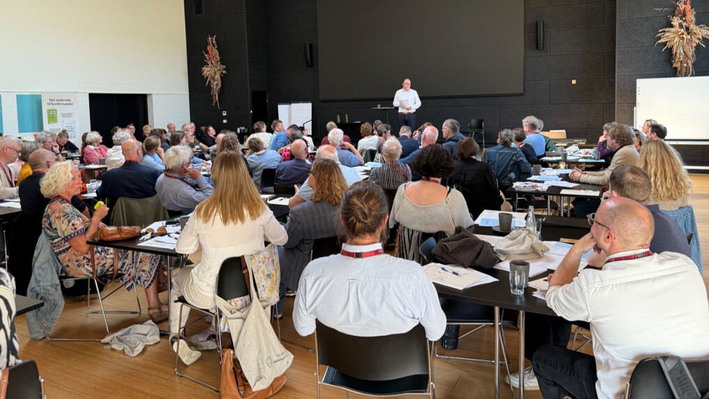 Sal fuld af præster og biskop på scenen